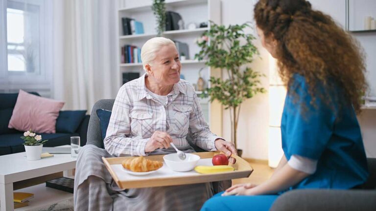 Adult daughter reviewing a medication list with an older parent at a bright kitchen table.
