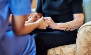 Older adult and family member review a daily care checklist at a kitchen table.