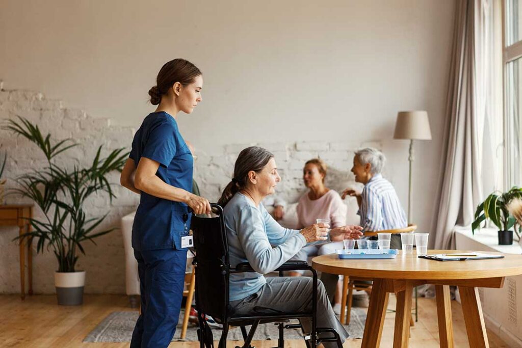 Older adult speaking with a caregiver in a bright assisted living apartment.