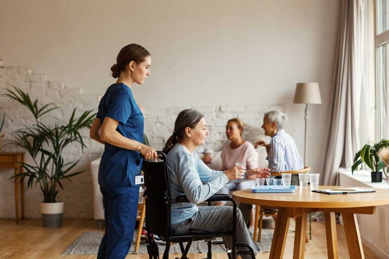 Older adult speaking with a caregiver in a bright assisted living apartment.